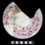 Painted floral luster decoration against pink luster band on white earthenware saucer. 